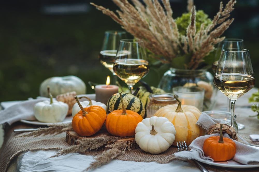 A cozy fall dinner table decorated with small pumpkins, candles, wine glasses, and autumn foliage — the perfect setting for easy comfort food recipes for fall.